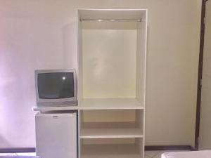 a tv sitting on a shelf next to a refrigerator at Pousada Central in Feira de Santana
