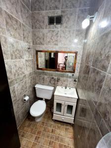 ein Badezimmer mit Toilette, Waschbecken und Spiegel in der Unterkunft Maraja318X in Mar de Ajó