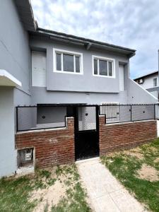 ein weißes Haus mit einer Tür und einer Ziegelmauer in der Unterkunft Maraja318X in Mar de Ajó