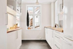a white kitchen with white cabinets and a window at Dinbnb Home - History meets Modern I 3-Story Bergen House in Bergen