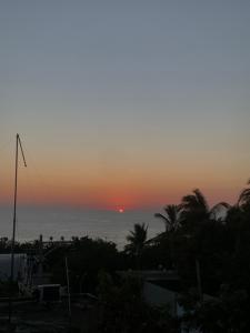einen Sonnenuntergang über dem Meer mit Palmen in der Unterkunft Habitaciones Nava in Brisas de Zicatela