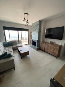 a living room with a couch and a flat screen tv at Premium Luxury Condo with breathtaking views in Loutraki