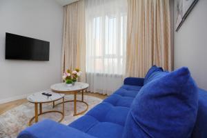 a living room with a blue couch and a tv at Central Light Apartment in Almaty
