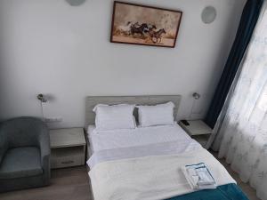 a bedroom with two beds and a chair and a picture on the wall at Pensiune Agroturistica CASA LETEA in Letea
