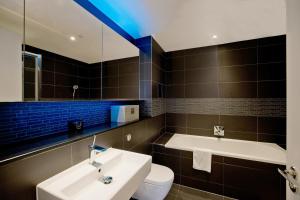 a bathroom with a tub and a sink and a toilet at Luxury 360 Penthouse with gym & parking in London