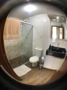 a bathroom with a toilet and a sink and a mirror at Pousada Soares in Piçarras