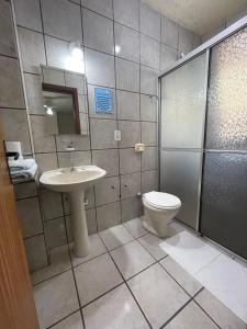 a bathroom with a toilet and a sink and a shower at Hotel Cambirela in Palhoça +64 photos
