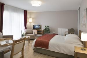 ein Hotelzimmer mit einem Bett, einem Schreibtisch und einer Couch in der Unterkunft Résidence Séniors Domitys "Les Portes de l'Atlantique" in Saint-Nazaire + 10 Fotos