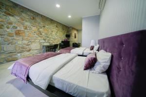 a bedroom with two beds and a stone wall at Alojamento Galerias Nascentes in Alijó