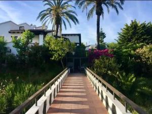 una pasarela frente a una casa con palmeras en Spacious House in Calafell with Shared Pool, en Calafell