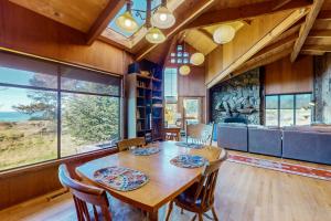 a dining room with a table and chairs and windows at Meyer Getaway in Sea Ranch