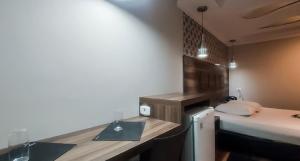 a small room with a bed and a desk with a sink at Motel Makakus in Sao Paulo