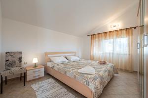 a bedroom with a bed and a chair and a window at Vladivostok Apartments in Tivat