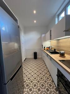a kitchen with a refrigerator and a tile floor at Maison Cosy en centre-ville in Libourne +9 photos