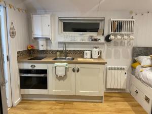 a small kitchen with white cabinets and a sink at Hillview Haven in Liskeard