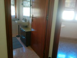 a bathroom with a sink and a wooden door at Cappuccini apartments superior in Oristano +56 photos