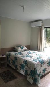 a bedroom with a bed with a floral bedspread at Pousada Oliveira in Ametista do Sul