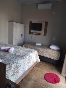 a bedroom with two beds and a tv on the wall at Pousada Oliveira in Ametista do Sul
