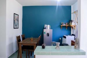 a kitchen with a blue wall and a table and a refrigerator at Casa Aurelia in Mazunte