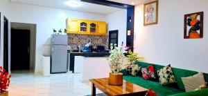 a living room with a green couch and a kitchen at Dar Noureddine in Lalla Takerkoust