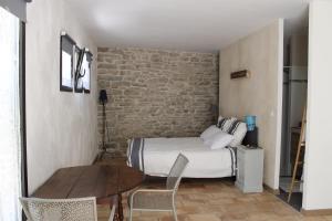 ein Schlafzimmer mit einem Bett, einem Tisch und einer Ziegelwand in der Unterkunft La Rôse in Saint-Gervasy