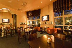 a restaurant with tables and chairs and windows at ARVENA Kongress Hotel - Hotel in der Wagnerstadt in Bayreuth