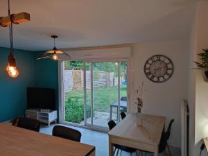 a dining room with a table and a clock on the wall at Ty Moon in Lannion