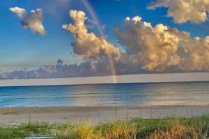a rainbow in the sky over the ocean with a beach at Beachfront Coastal Cottage St George Island in St. George Island