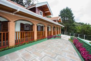 a house with a patio and flowers in front of it at Pousada Vila Floratta in Campos do Jordão