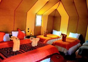 a room with three beds with orange sheets at Amazing Luxury Camp in Merzouga