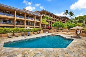 a resort with a swimming pool and chairs and a building at Kona Pacific B-308 in Kailua-Kona