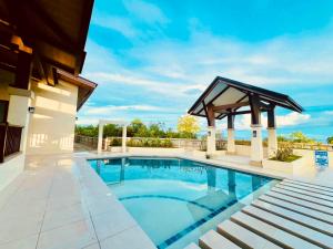 a swimming pool with a gazebo next to a house at Royal Oceancrest Panglao I in Dauis