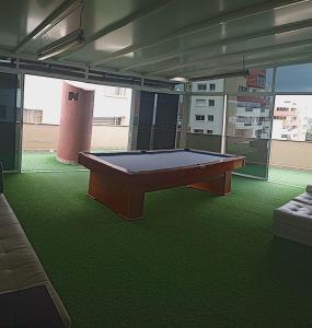 a ping pong table in a room with green carpet at Playa Almendro Resort - Tonsupa in Tonsupa