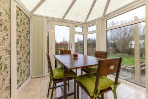 ein Wintergarten-Esszimmer mit einem Holztisch und Stühlen in der Unterkunft Wootton 2-Bedroom Bungalow in Hardingstone