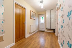 Zimmer mit einer Tür und einem Flur mit Holzböden in der Unterkunft Wootton 2-Bedroom Bungalow in Hardingstone