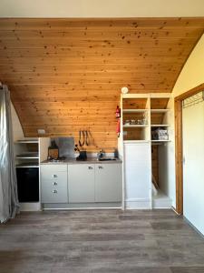 a kitchen with white cabinets and a wooden ceiling at Welly Boot Pod in Shenstone