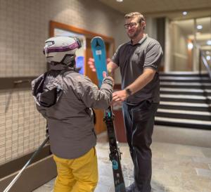 a man standing next to a man with skis at Listel Whistler, a Coast Hotel in Whistler