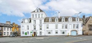 a large white building with a tower on a street at The Lakeland Kendal Hotel, Sure Hotel Collection by Best Western in Kendal
