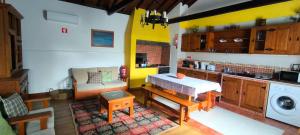 a kitchen with a table and a couch in a room at Casal do Vulcão in Capelo