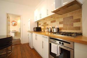 a kitchen with white cabinets and a stove top oven at Old Compton Street in London