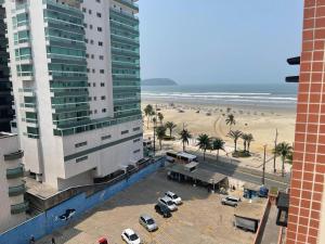 - une vue sur un bâtiment et une plage bordée de palmiers dans l'établissement Apto Beiramar com piscina em Praia Grande, à Praia Grande