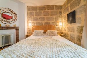 una camera da letto con un letto con un muro di pietra di Escale de Dali - 1 Chambre a Brive-la-Gaillarde