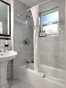 La salle de bains blanche est pourvue d'un lavabo, d'une baignoire et d'une douche. dans l'établissement Cherokee Lodge, à San Diego 37 autres photos