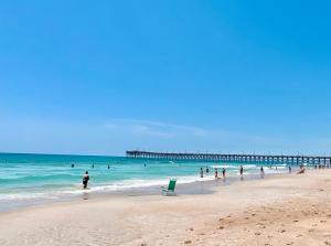 a group of people on a beach with a pier at 1004 Queen Pet Friendly Suite, 1st Floor Oasis in Surf City