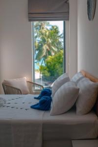 a bed with pillows and a window with a palm tree at Atoll Retreat in Fulidhoo +58 photos