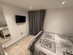 Un dormitorio con una cama y un televisor de pantalla plana. en Luxe Guesthouse, en Stoke on Trent