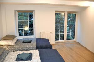 a bedroom with two beds and two large windows at Apartament Starówka Piastowska in Olsztyn