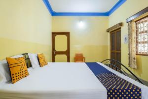 ein Schlafzimmer mit einem großen weißen Bett mit bunten Kissen in der Unterkunft SPOT ON Cherish Guest House in Ranchi