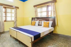 Schlafzimmer mit einem Bett mit gelben Wänden und Fenstern in der Unterkunft SPOT ON Cherish Guest House in Ranchi + 26 Fotos