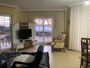 ein Wohnzimmer mit einem TV und einem Balkon in der Unterkunft Kaş Güzey apart 3+1 Doğa ve deniz manzaralı in Kaş